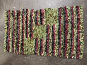 A rag rug, 78cm by 130cm approximately, in several colours, predominately shades of green, raspberry