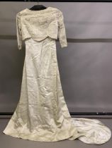 A 1960’s cream wedding dress, slim-line, fitted machine lace bodice integral to the rear and loose