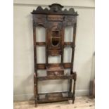 An oak Green man style hall stand with heavily carved pediment above oval mirror above short