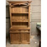 A reproduction, heavily carved pine kitchen dresser, the top with three shelves, the middle shelf