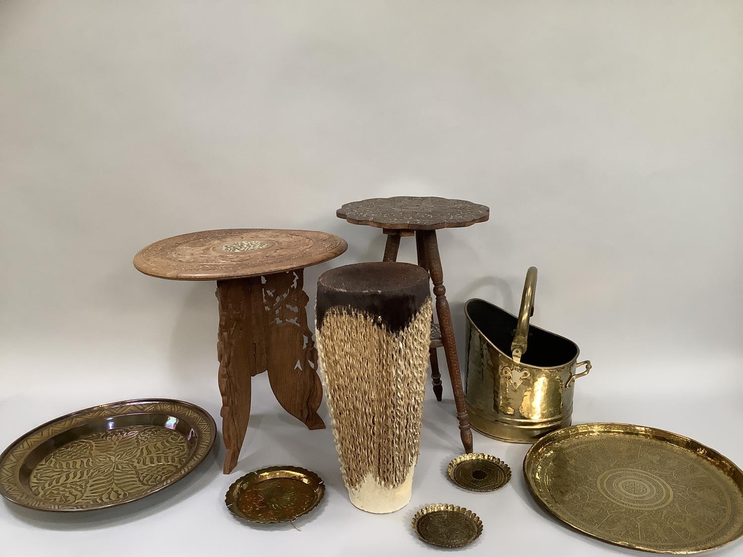 Two Middle Eastern carved tables, two Middle Eastern etched and moulded brass trays, brass coal