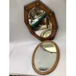 A 20th century oak shield shaped mirror with oval glass together with an oval oak mirror