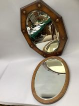 A 20th century oak shield shaped mirror with oval glass together with an oval oak mirror