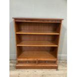 A reproduction bookshelf with three shelves above two short drawers and on pediment base