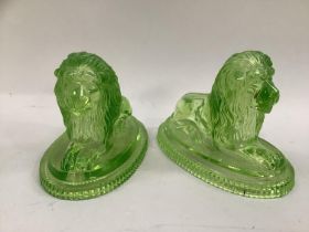 A pair of John Derbyshire moulded green glass lions in recumbent posh on bases bearing anchor and