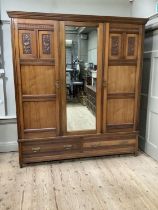 An Edwardian walnut triple wardrobe having central mirrored panel with fitted interior of two slides