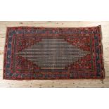 A MIDDLE EASTERN RUG, the wine coloured field having a stepped lozenge medallion filled with