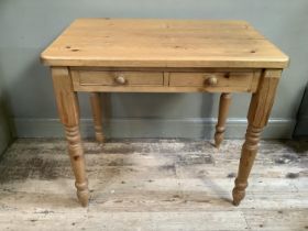 A pine kitchen table with two drawers, on turned legs, 91cm by 60cm