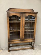An early 20th century oak glazed bookcase on barley twist supports with stretcher and carved back
