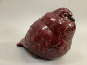 A French ceramic model of a cooing pigeon shown with feathers ruffled in a maroon glaze, 14cm high