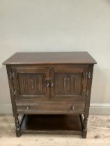 An oak reproduction Old Charm style cupboard of two doors above long drawer with lower tier on