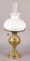 A Victorian brass oil lamp, having a wrythen embossed 'cup and cover' reservoir and conforming domed