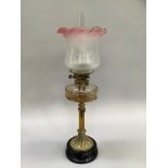 A Victorian oil lamp with glass reservoir and reeded support on black stepped base, having an opaque