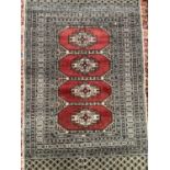 A woven woollen Middle Eastern rug, having four wine lozenge medallions in a cream field 144cm x