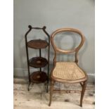 Edwardian mahogany three tier cake stand together with a balloon back chair with cane seat on turned