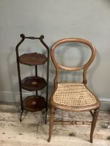 Edwardian mahogany three tier cake stand together with a balloon back chair with cane seat on turned
