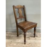 An Edwardian oak hall chair on tuned legs with scrolled back