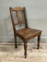 An Edwardian oak hall chair on tuned legs with scrolled back