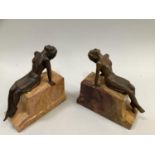 Art Deco style bookends of bronzed female reclining figures on ochre marble stepped plinth, 17cm