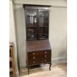 A 20th century mahogany bureau bookcase with two glazed doors above drop leaf, the interior fitted