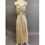 A 1930’s ivory satin gown with gold lamé trimmed bodice, covered buttons to rear, flared skirt