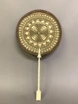 A very unusual face screen or fixed fan, the circular screen fixed to a turned bone handle, in the