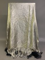 A 1920’s lamé shawl, silver, subtly designed with flowers, with fringing shaded from silver to grey