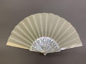 A white Mother of Pearl fan, with a hint of colour, the guards and gorge with decorative piercing