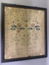 A large early 19th century sampler worked in silks on canvas, designed with several formal flower