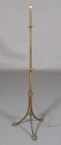 AN EDWARD VII EMBOSSED GILT METAL STANDARD LAMP on tripod base with palmette feet