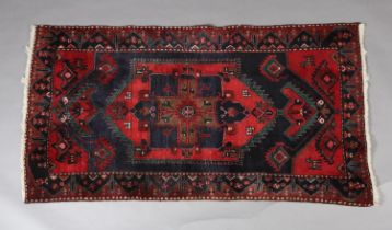 A PERSIAN KAYMAN WOOL RUG, the dark blue ground having a central medallion and spandrels in red
