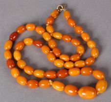 AN EARLY 20TH CENTURY AMBER NECKLACE of graduated oval beads, maximum approximately 20mm x 14mm,