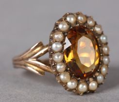 A VICTORIAN CITRENE AND SEED PEARL CLUSTER RING in 9ct gold, set to the centre with an oval facetted