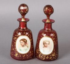 A NEAR PAIR OF 19TH CENTURY BOHEMIAN RUBY COLOGNE BOTTLES with gilt, white overlay cartouche painted