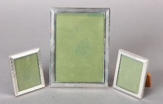 AN ELIZABETH II SILVER PHOTOGRAPH FRAME, and a pair of matching small photograph frames,