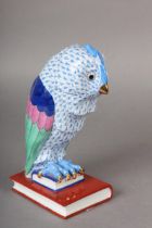 A HEREND PORCELAIN FIGURE OF AN OWL PERCHED ON BOOKS, hand painted in blue scale, dark blue, pink