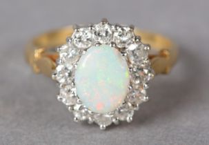 AN OPAL AND DIAMOND CLUSTER RING in 18ct gold, claw set to the centre with an oval cabochon opal