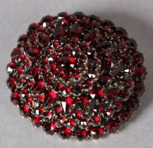 A LATE 19TH CENTURY BOHEMIAN GARNET CLUSTER BROOCH, tiered within an oval surround in gilt base