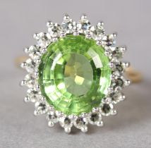 A PERIDOT AND DIAMOND CLUSTER RING in 18ct yellow and white gold, claw set to the centre with an