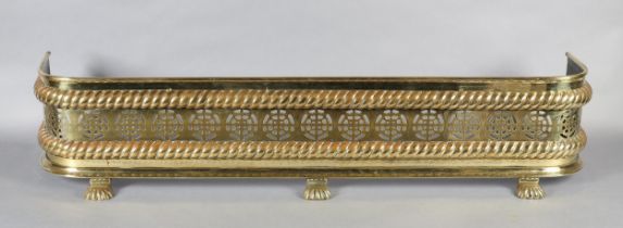 A MID VICTORIAN BRASS FENDER, of pierced circular decoration between two rope twist borders, on