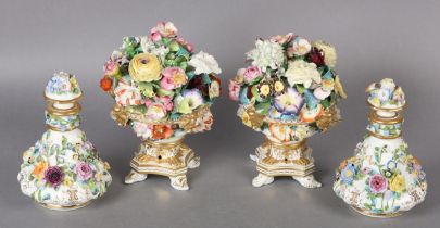 A PAIR OF 19TH CENTURY PORCELAIN URNS ENCRUSTED WITH FLOWERS on three shell feet 18cm high,