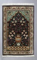 A HAND KNOTTED SILK RUG, modern, the dark blue field filled with flowers held in an urn beneath an