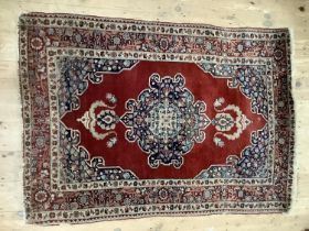 A middle Eastern rug, the wine coloured ground with central medallion with blue floral filled