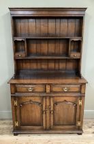 A Tichmarsh and Goodwin oak dresser and rack having a moulded cornice above a planked back with