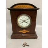 An early 20th century mahogany and satinwood inlaid mantel clock having an arched profile above a