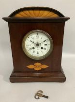 An early 20th century mahogany and satinwood inlaid mantel clock having an arched profile above a