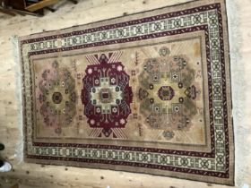 A middle Eastern rug, the pale camel ground having wine coloured and pale pink medallions with