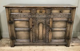 An oak dresser base having three indented panel drawers across above two indented panel doors with