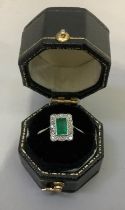 An emerald and diamond dress ring c1950 in 18ct gold and platinum, the baguette cut emerald collet