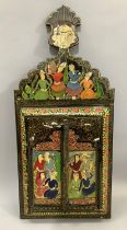 A Persian lacquered wall mirror having two doors, painted with figures and flowers, having a